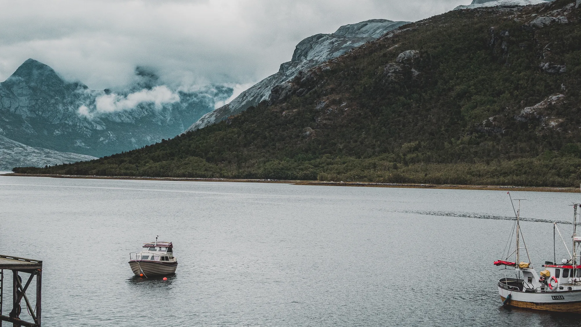 A fishing vessel moored in a still Icelandic fjord beneath mountains