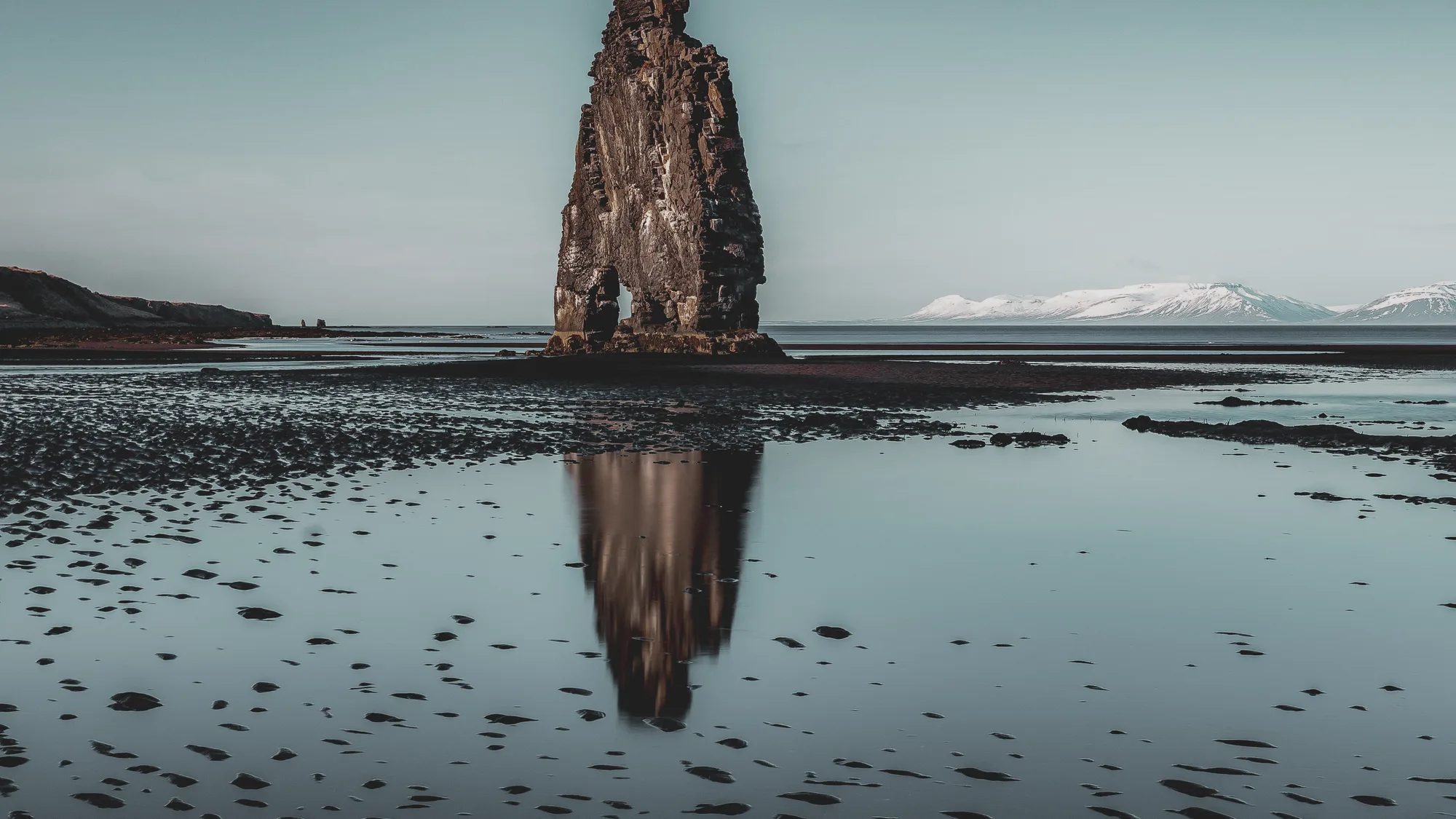 A sea stack mirrored in still water at low tide